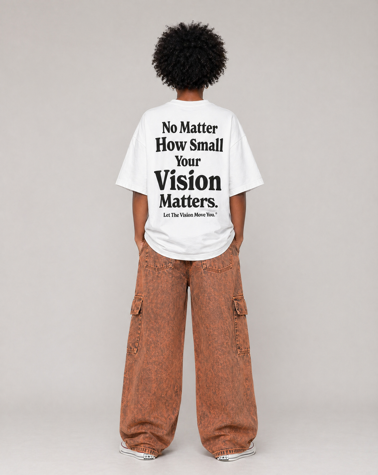 Person wearing a white t-shirt with motivational text on the back saying "No Matter How Small Your Vision Matters", standing against a plain background.