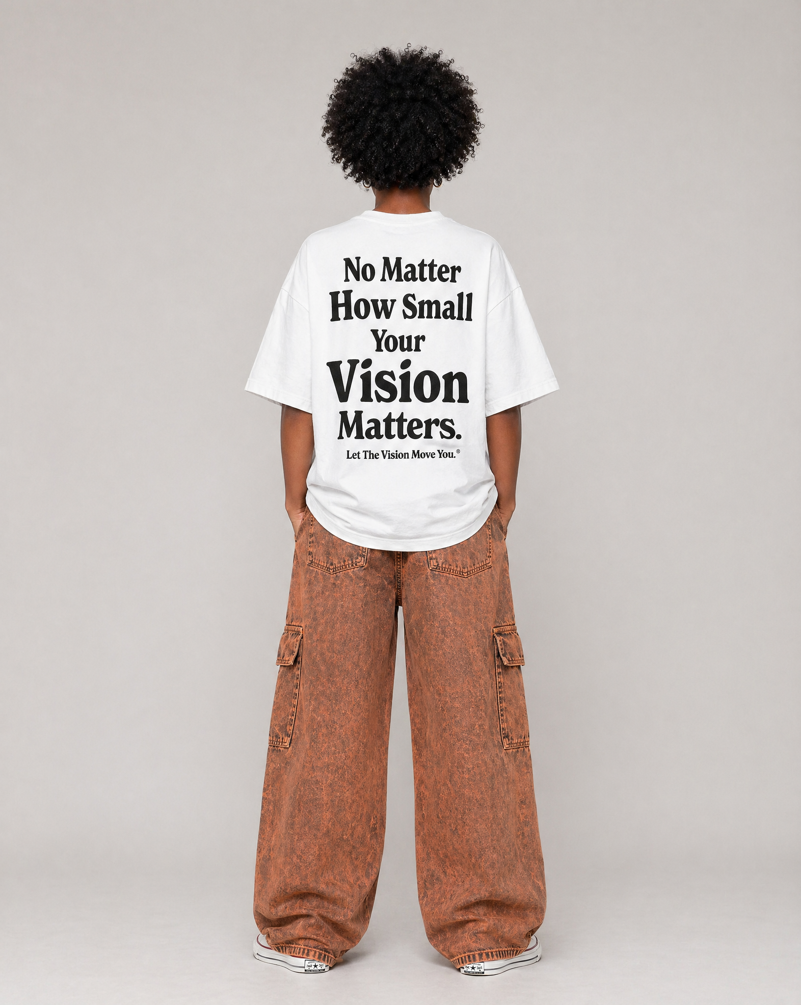 Person wearing a white t-shirt with motivational text on the back saying "No Matter How Small Your Vision Matters", standing against a plain background.