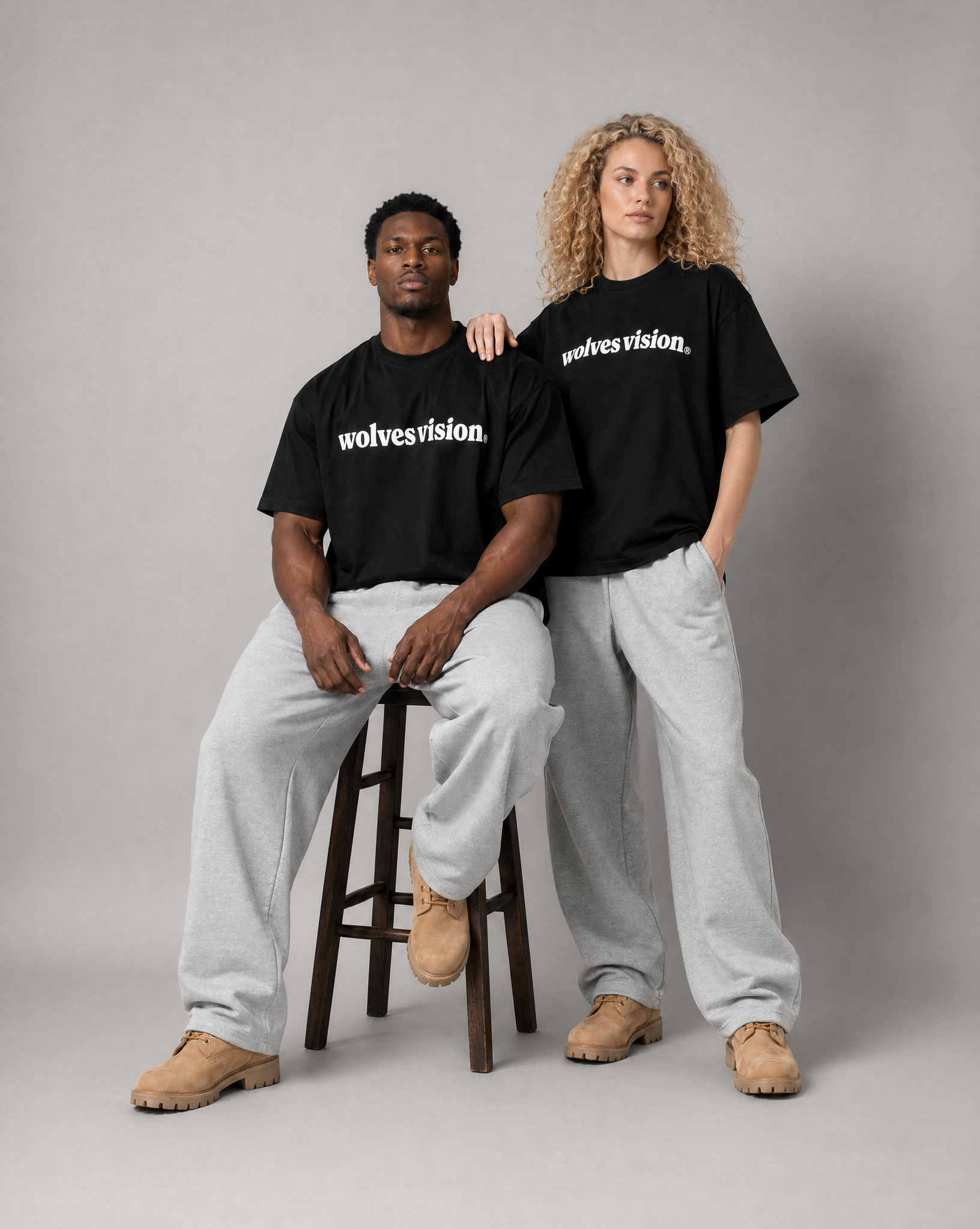 Two people wearing black 'wolvesvision' t-shirts on a gray background